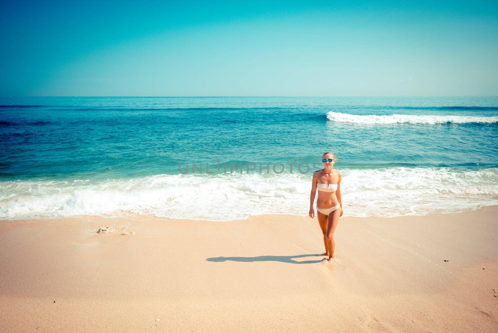 Young slim woman wearing bikini and sunglasses at the ocean beach