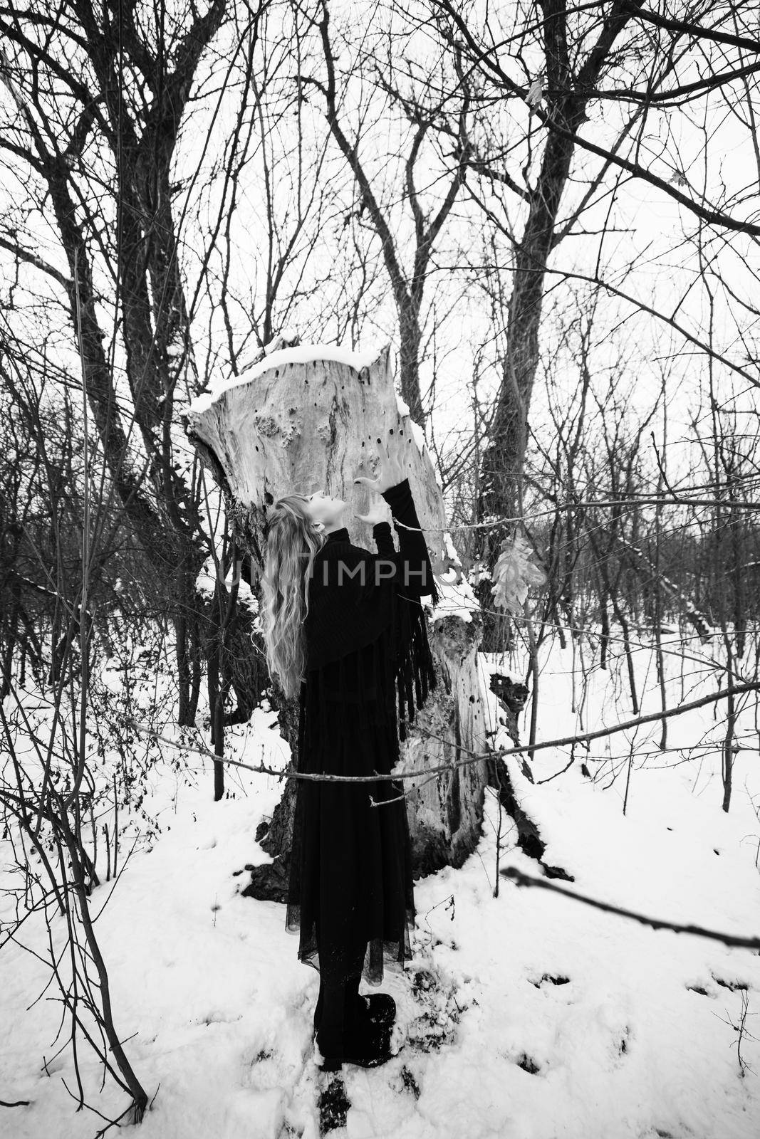 Depressed and lonely woman praying in forest in winter.