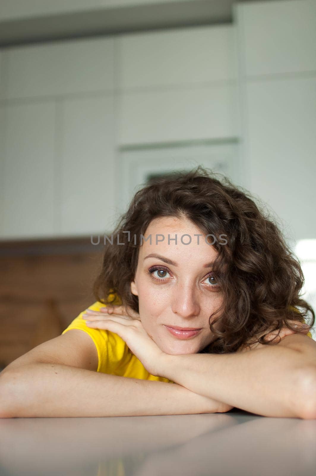 Beautiful curly girl in yellow t-shirt is looking at the camera at home in her apartment, posing with smile, happy people concept by balinska_lv