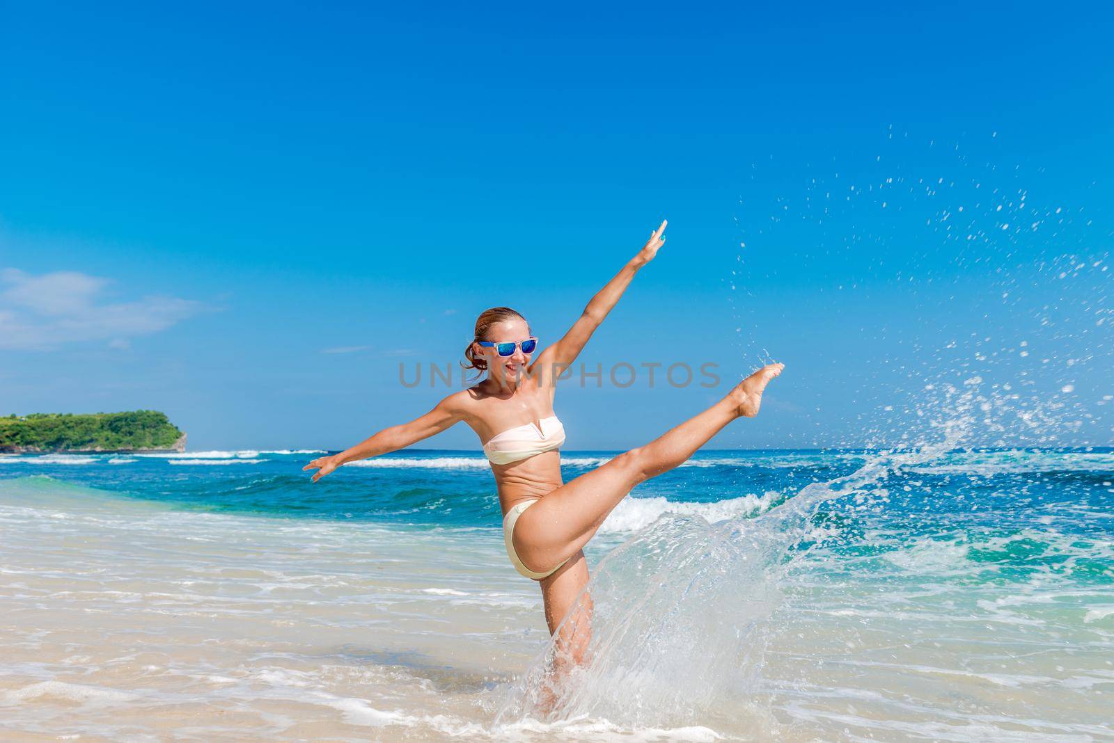 Young slim woman wearing bikini and sunglasses at the ocean beach