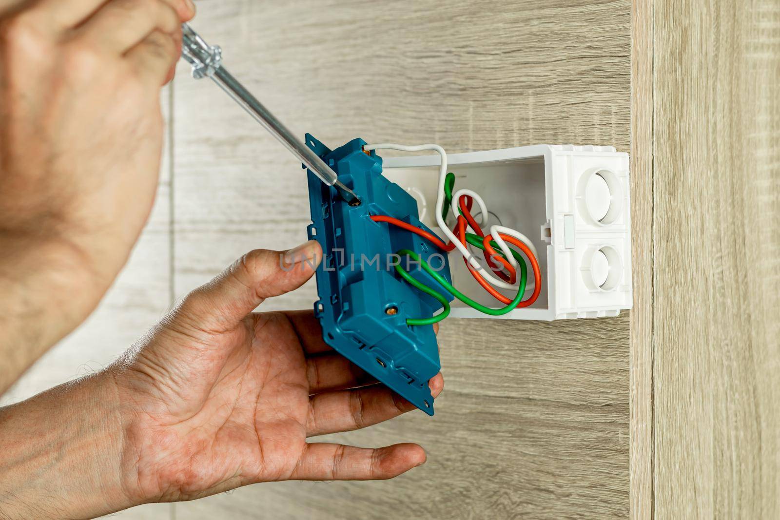 Remove the power electric plug socket from the outlet box on the wooden wall to check the voltage with a screwdriver. by wattanaphob