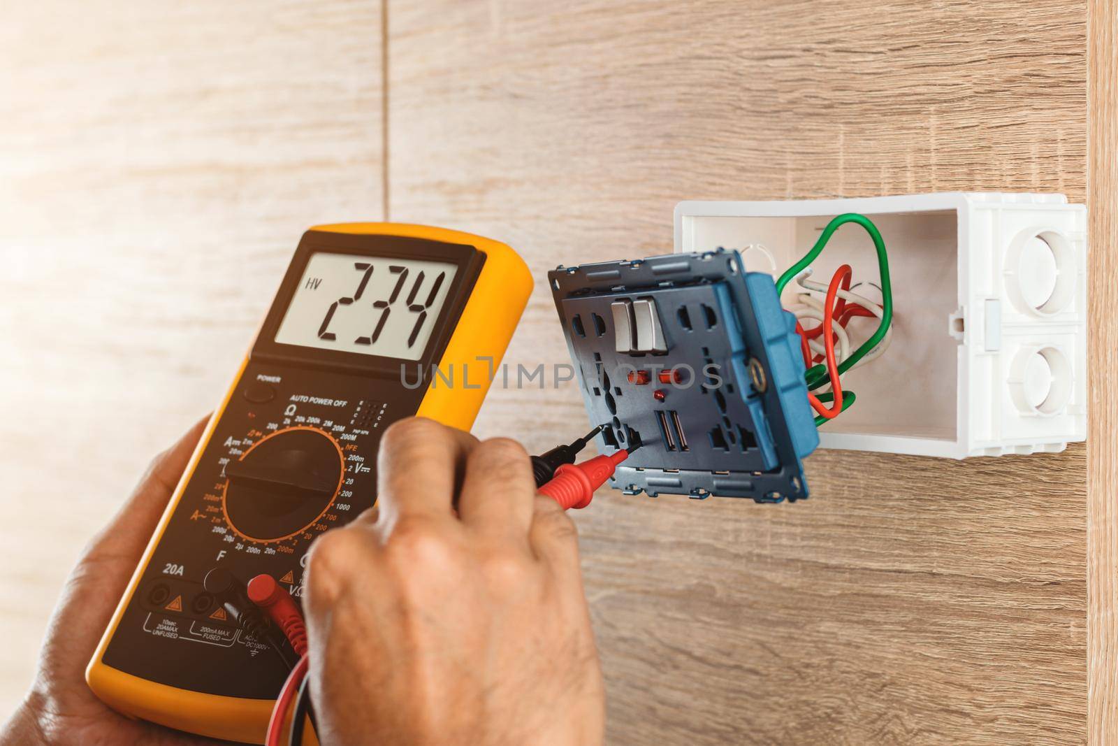 Remove the power electric plug socket from the outlet box on the wooden wall to measure the voltage with a digital meter.