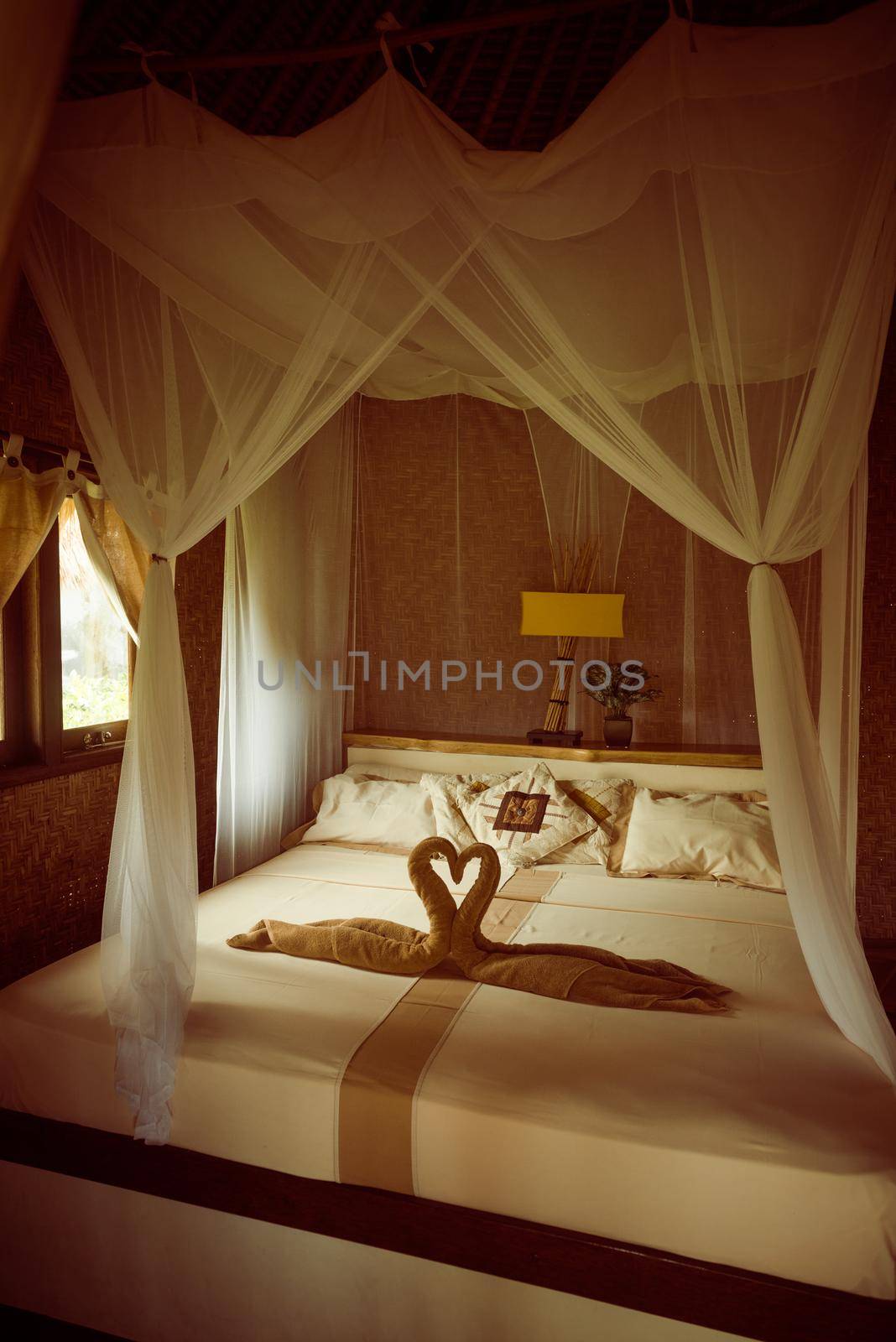 Bed with canopy and swans made of towels in bungalow