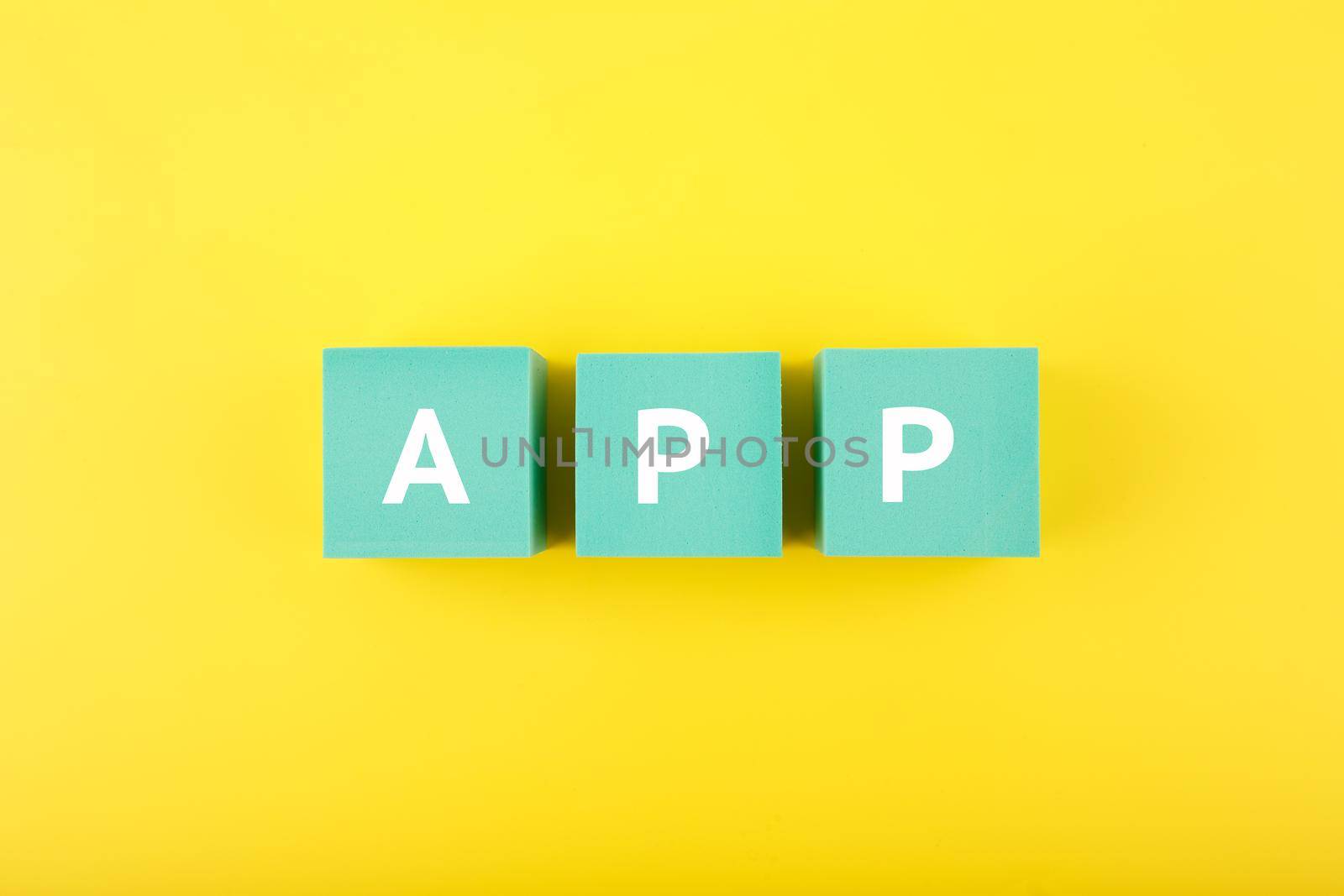 App written on blue cubes against bright yellow background by Senorina_Irina