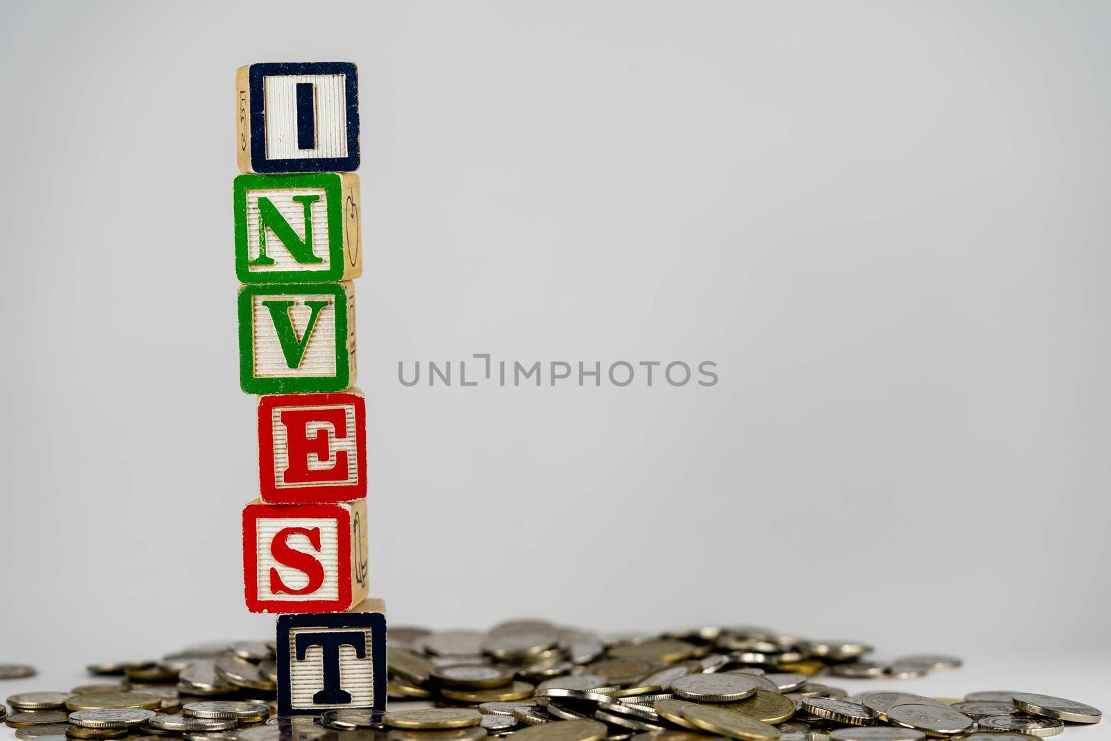 Investment concept with wooden blocks and coins. Invest letters on wooden blocks sorrounded with money