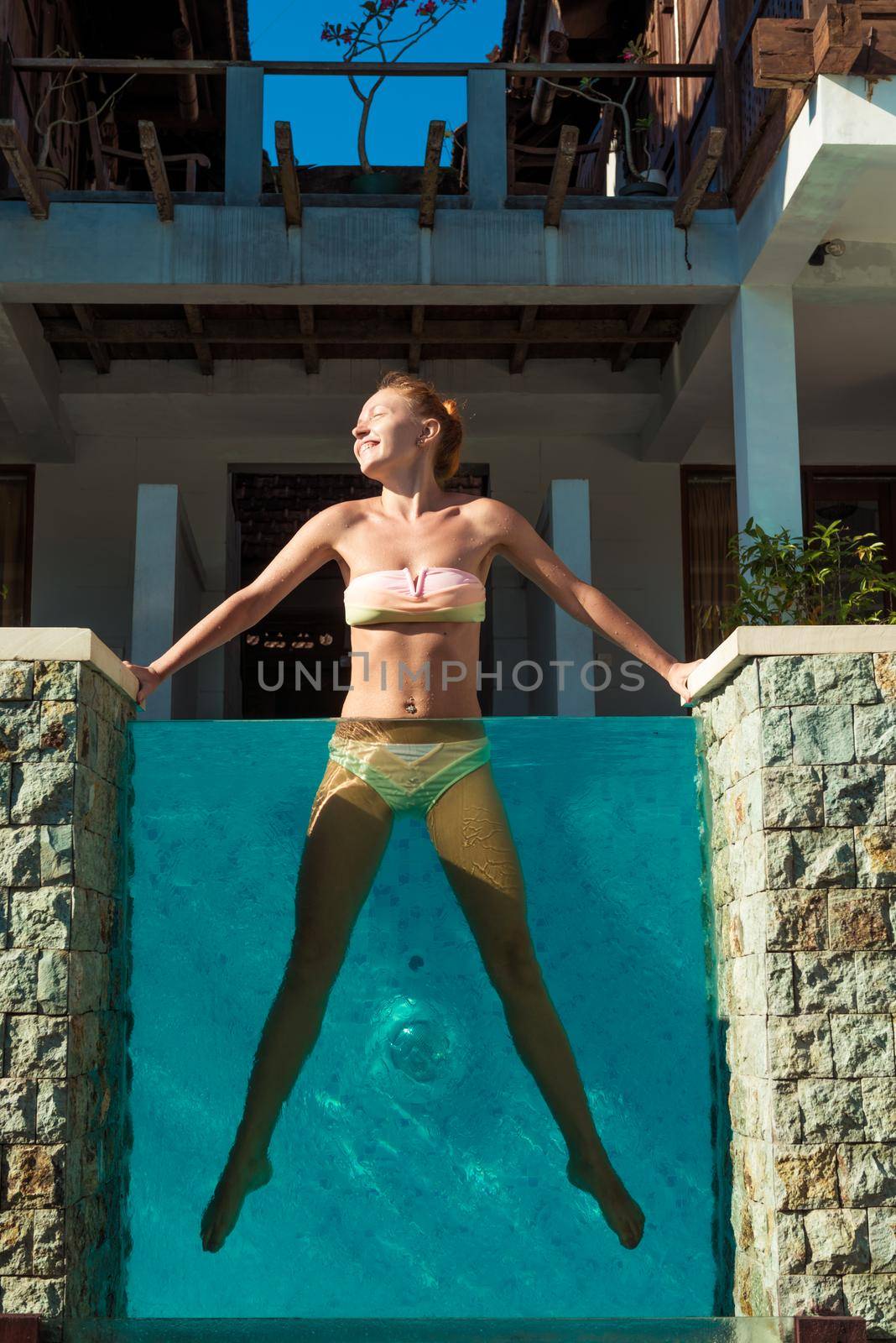 Young woman wearing swimsuit relaxing near swimming pool at exotic location