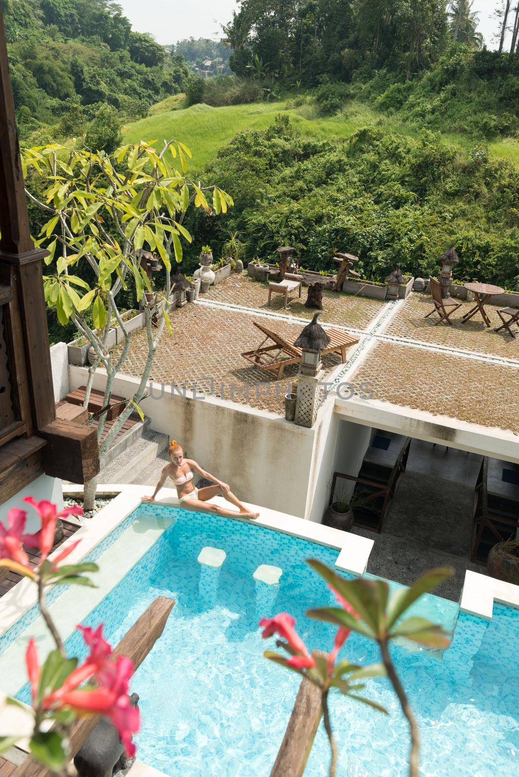 Young woman wearing swimsuit relaxing near swimming pool at exotic location