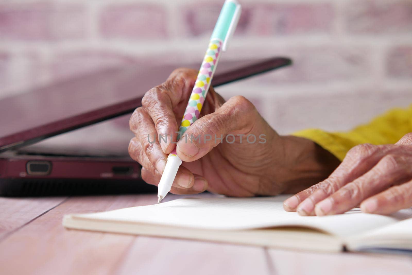 Close up of senior women hand writing on notepad.