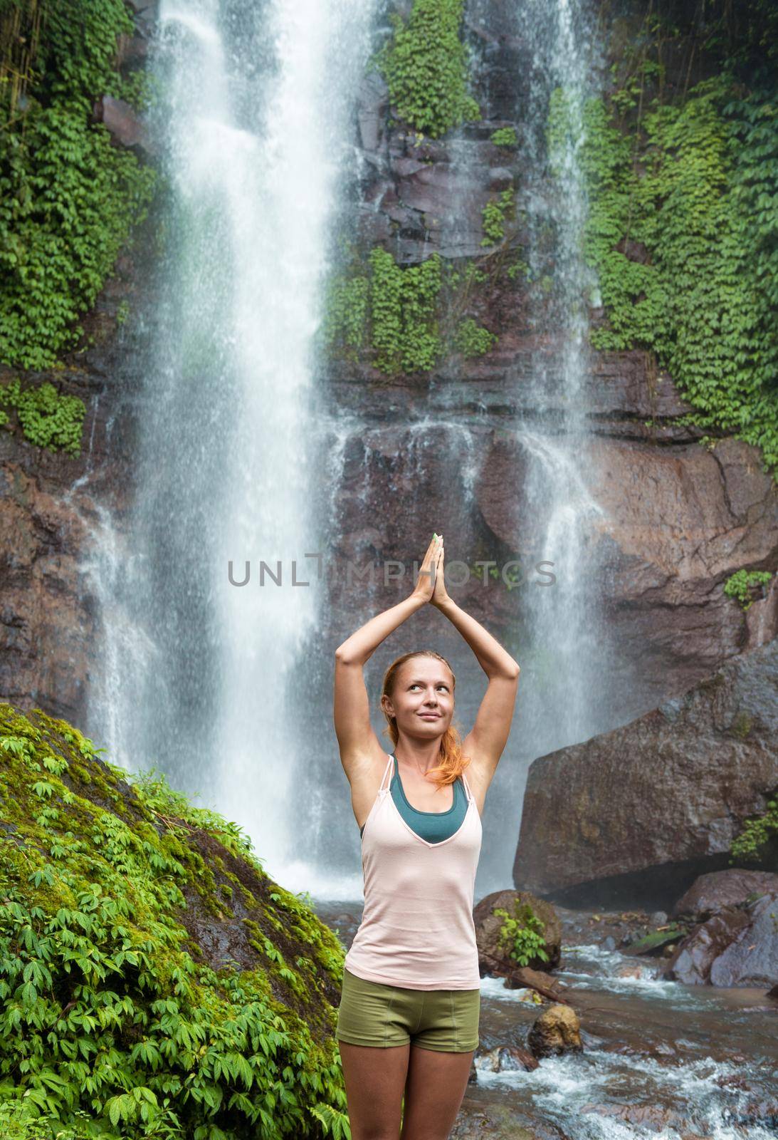 Young woman practicing yoga by the waterfall by nikitabuida