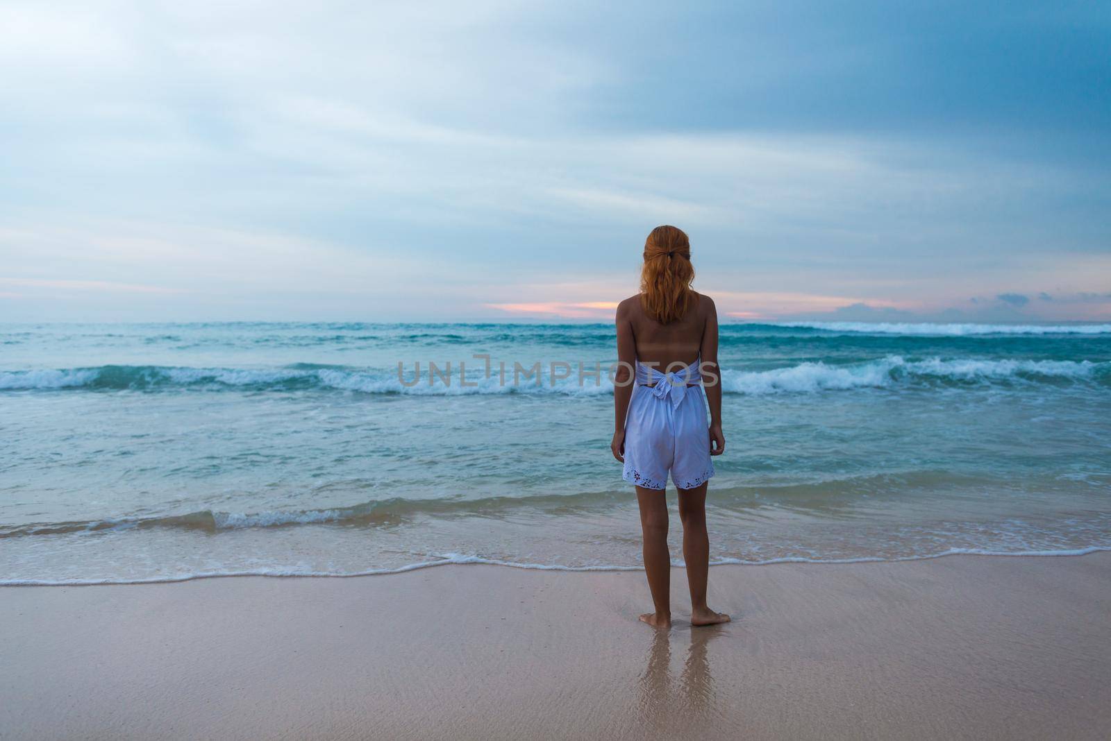 Young woman standing on ocean beach by nikitabuida