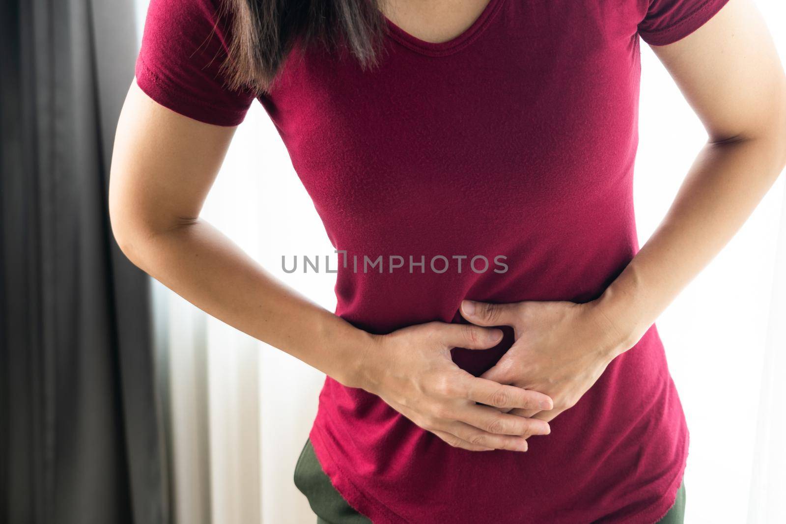 woman having painful stomachache at home. Chronic gastritis. Abdomen bloating concept by psodaz