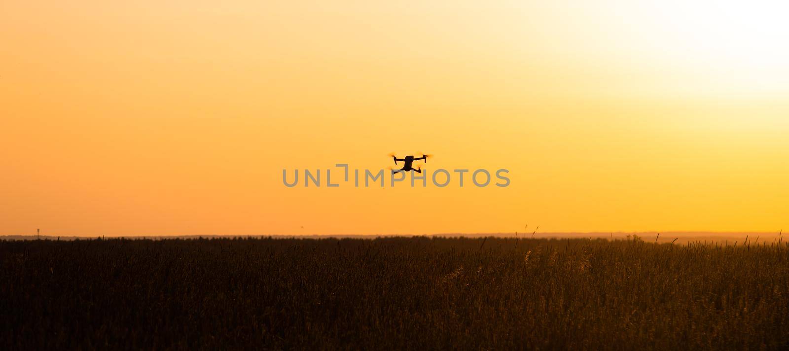 The drone is in flight at sunset . Video shooting from above. An article about the choice of a quadrocopter. Pros and cons of the drone. Sunset