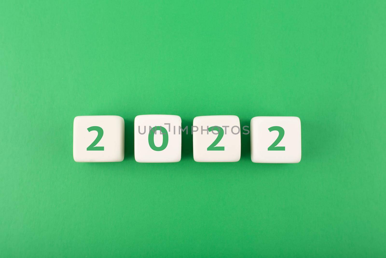 2022 numbers on white cubes against green background. Minimal elegant business style concept of New Year 