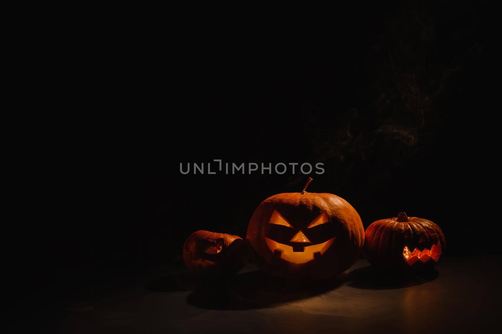 Pumpkins with carved grimaces and candles inside in the dark for halloween. Jack o latern in smoke. by mrwed54