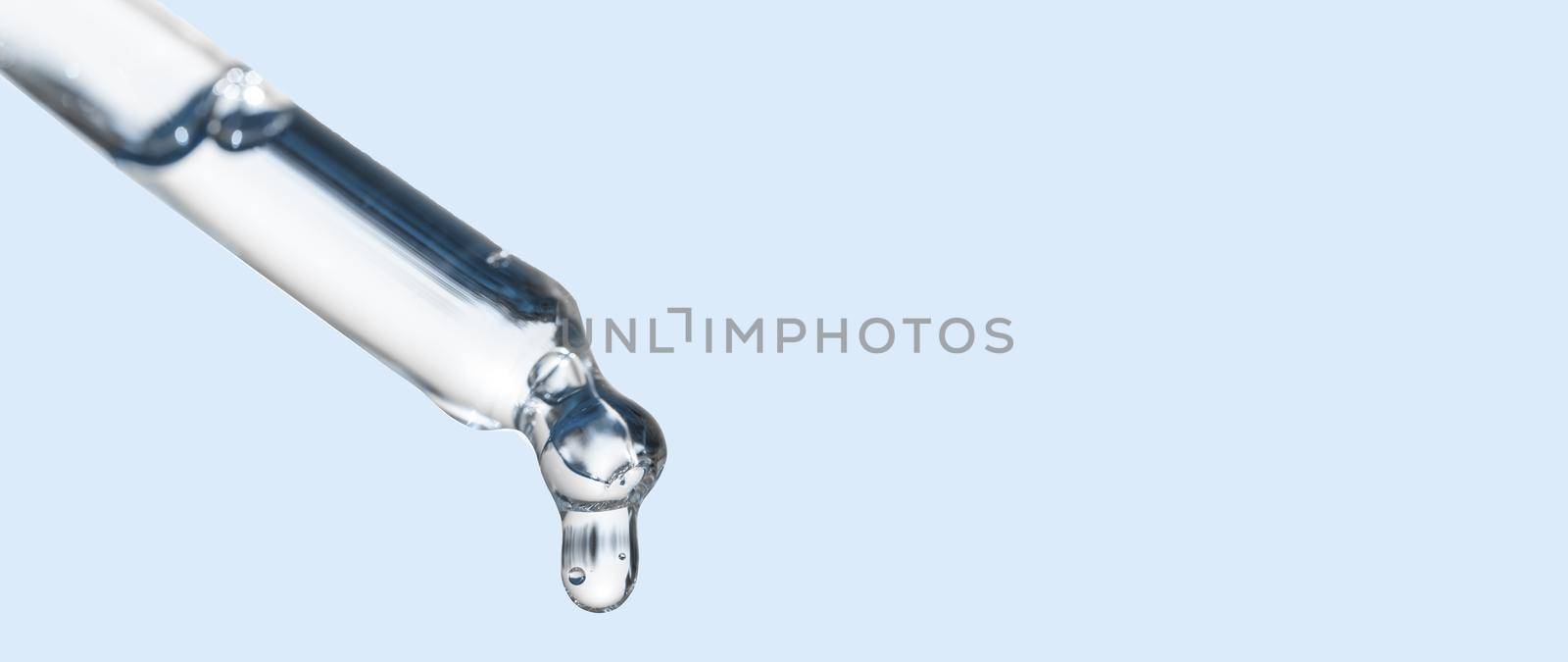 Cosmetics dropper, falling drop close up. Closeup of cosmetic pipette with essential oil dropping, serum with peptides on blue background. Self care concept. Beauty skin care product. by photolime