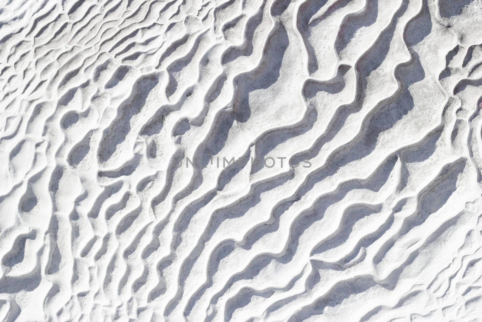 Gray-white texture background of Pamukkale calcium travertine in Turkey, pattern of diagonal waves, close-up.