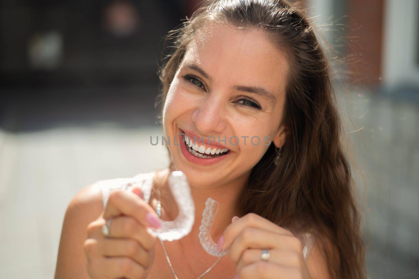 Beautiful caucasian woman holding transparent mouth guards for bite correction. by mrwed54