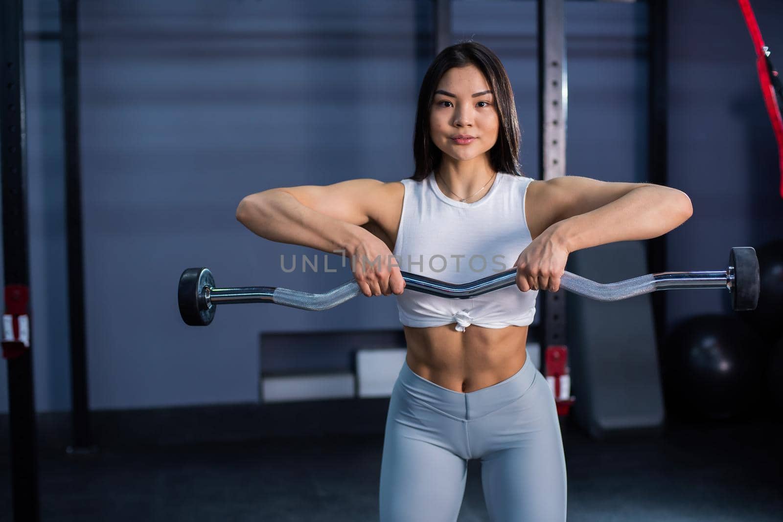 Asian woman doing exercises with dumbbells in the gym