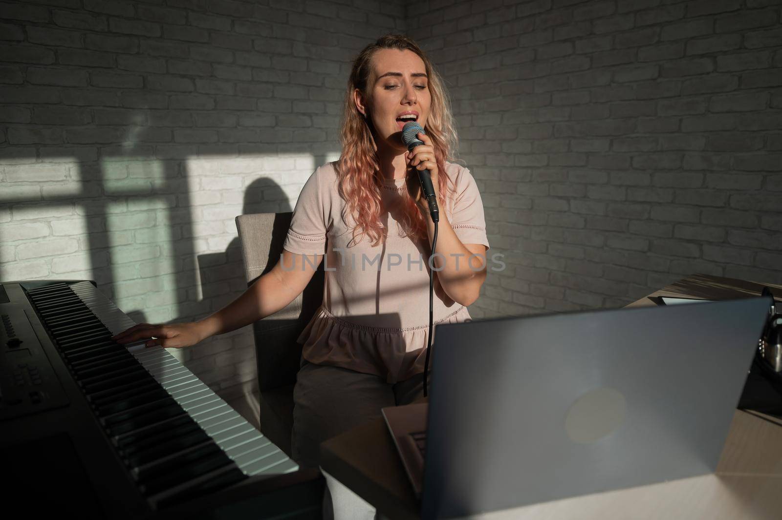 A female blogger sings and plays the live electronic piano. Portrait of a girl recording a song on a web camera and composing on a synthesizer. Online music lessons. Distance learning in quarantine