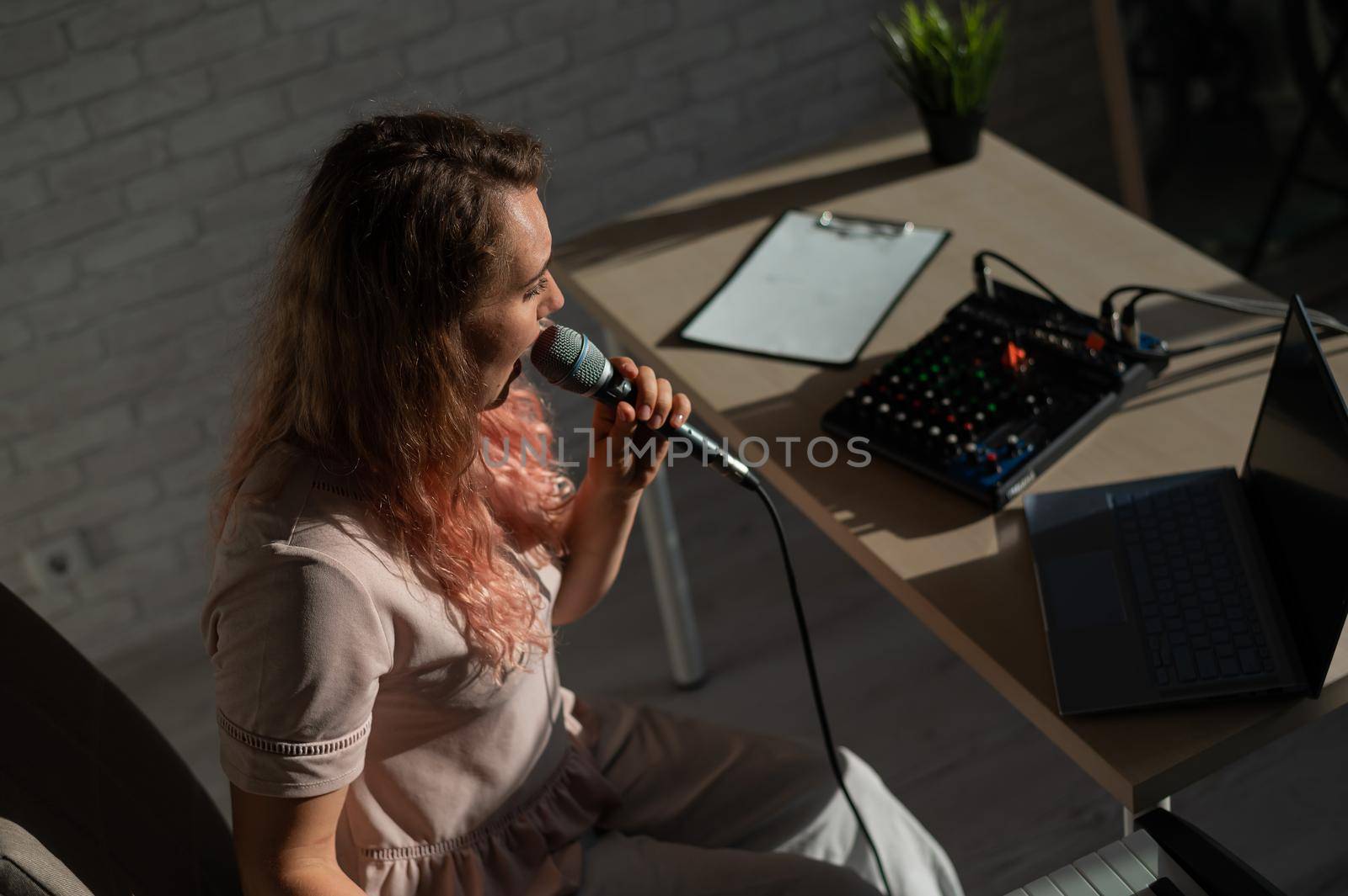 Expressive female singer has a video blog on a laptop. Portrait of a girl recording a song on a web camera and composing on a synthesizer. Online music lessons. Distance learning in quarantine. by mrwed54