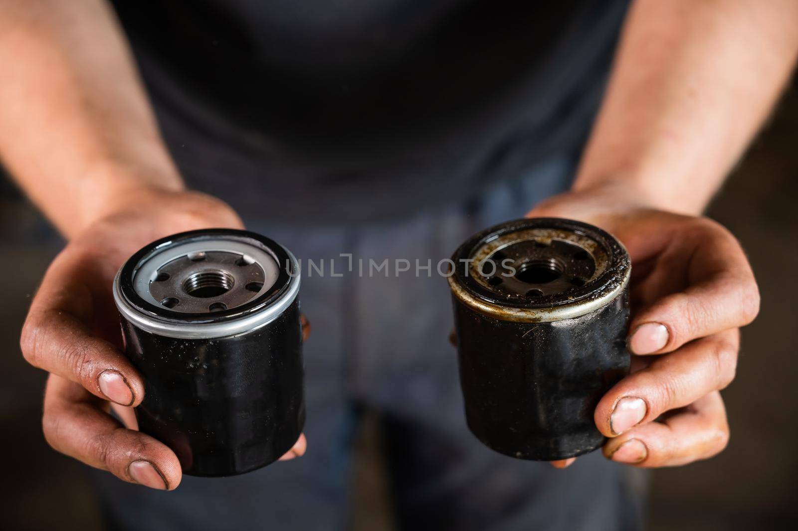 An auto mechanic holds a new and used oil filter