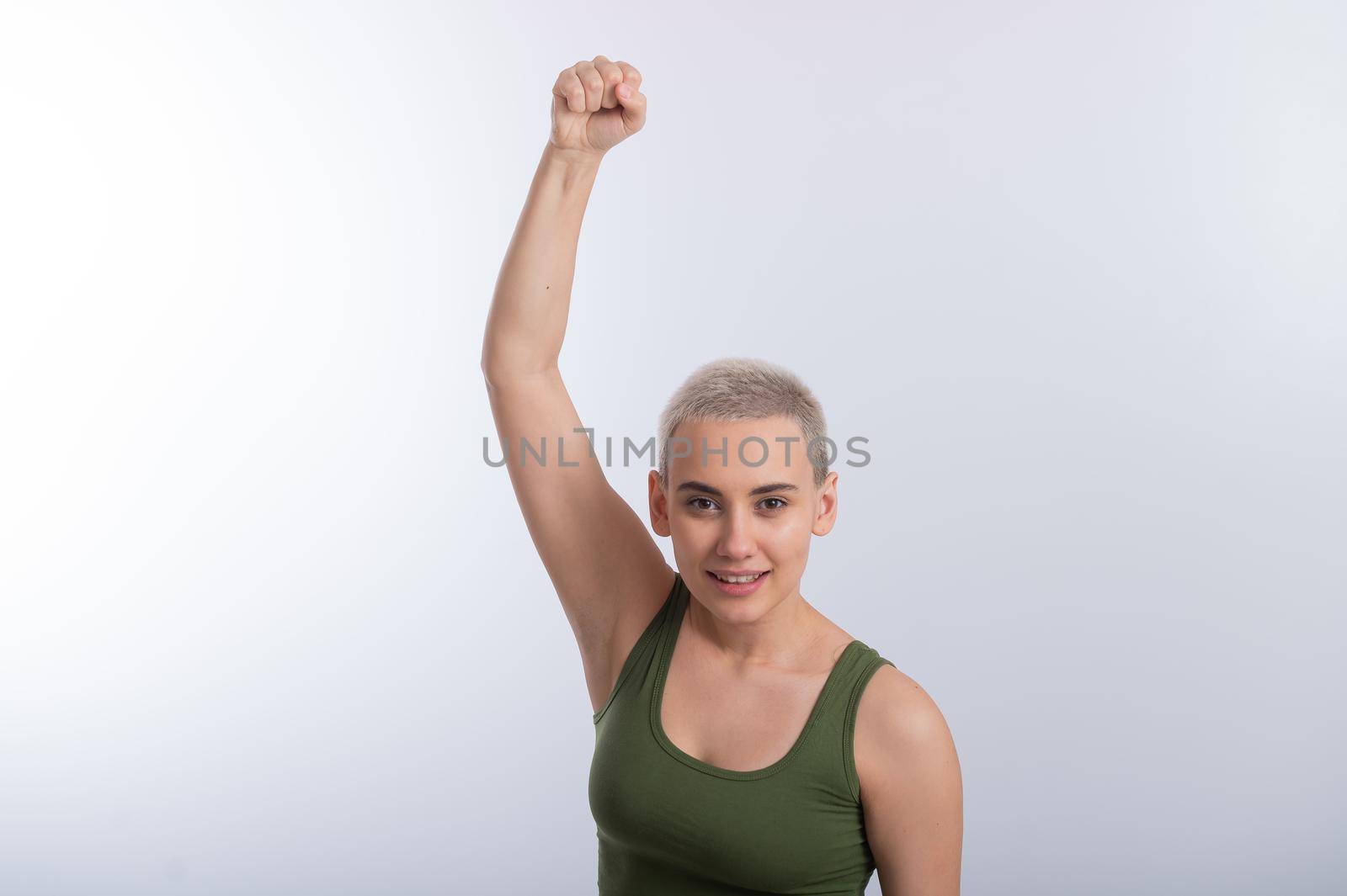 Young caucasian woman holding her fist up on a white background. A girl with short hair is fighting for rights.