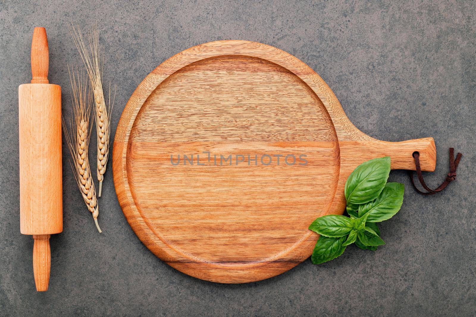 Empty wooden pizza platter set up on dark concrete. Pizza tray on dark concrete background flat lay and copy space. by kerdkanno