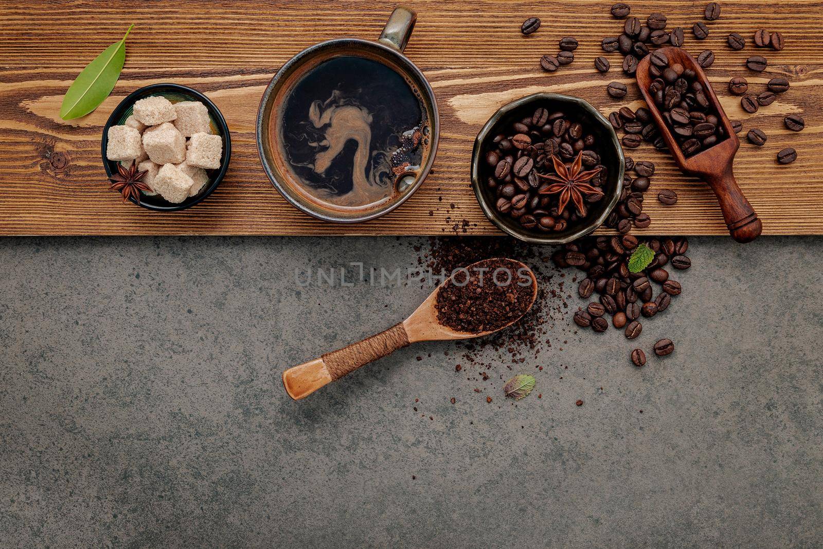 Roasted coffee beans with coffee cup setup on dark stone background.