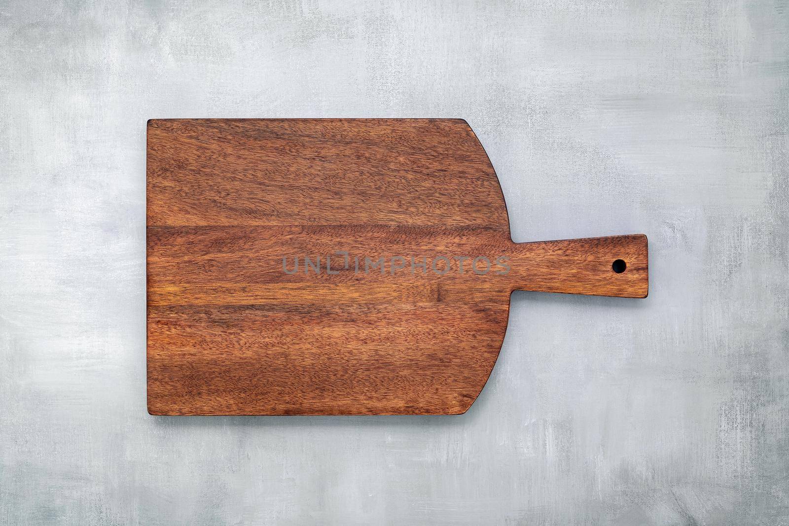 Empty vintage wooden cutting board set up on concrete background with copy space. by kerdkanno