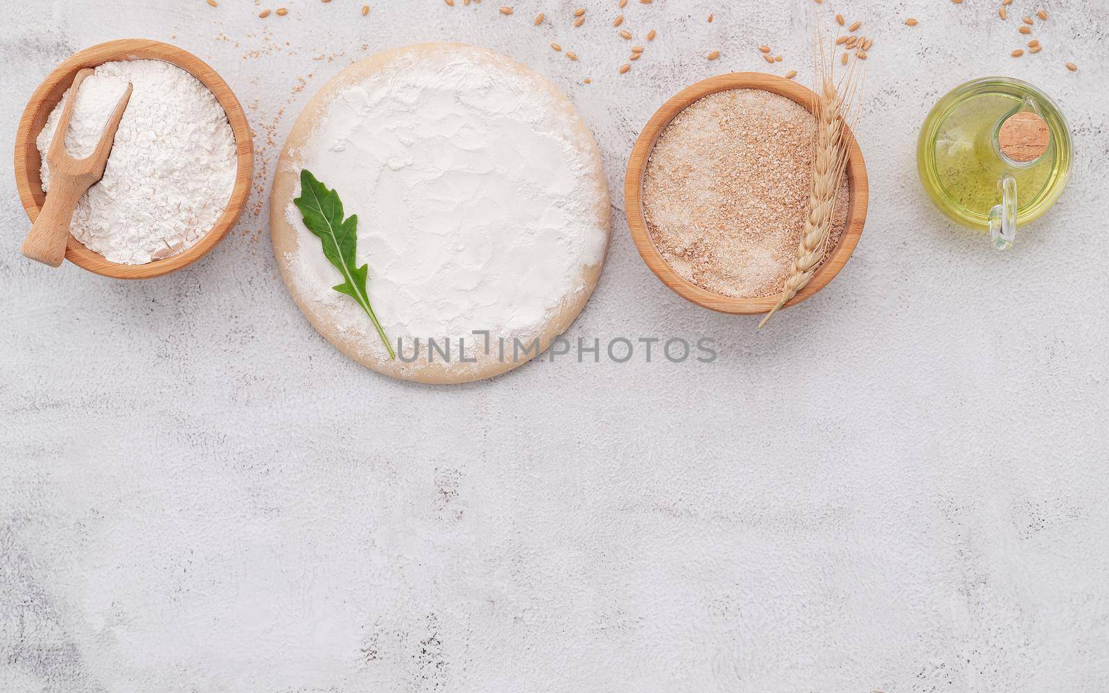 The ingredients for homemade pizza dough with wheat ears ,wheat flour and wheat grains set up on white concrete background. by kerdkanno
