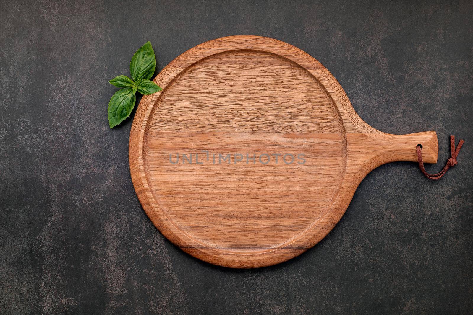 Empty wooden pizza platter set up on dark concrete. Pizza tray on dark concrete background flat lay and copy space. by kerdkanno