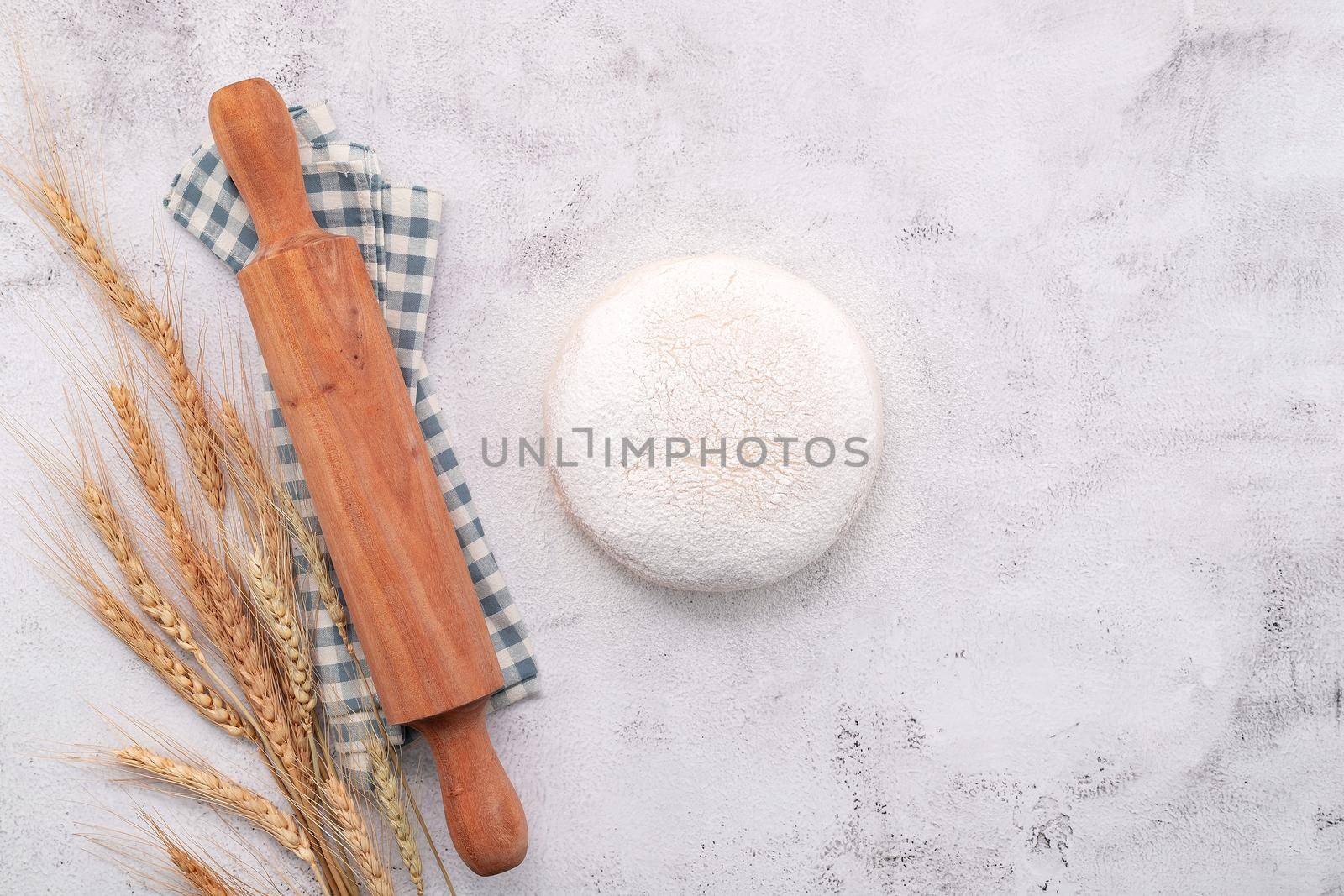 Wheat ears and wheat grains setup with rolling pin on white concrete background.