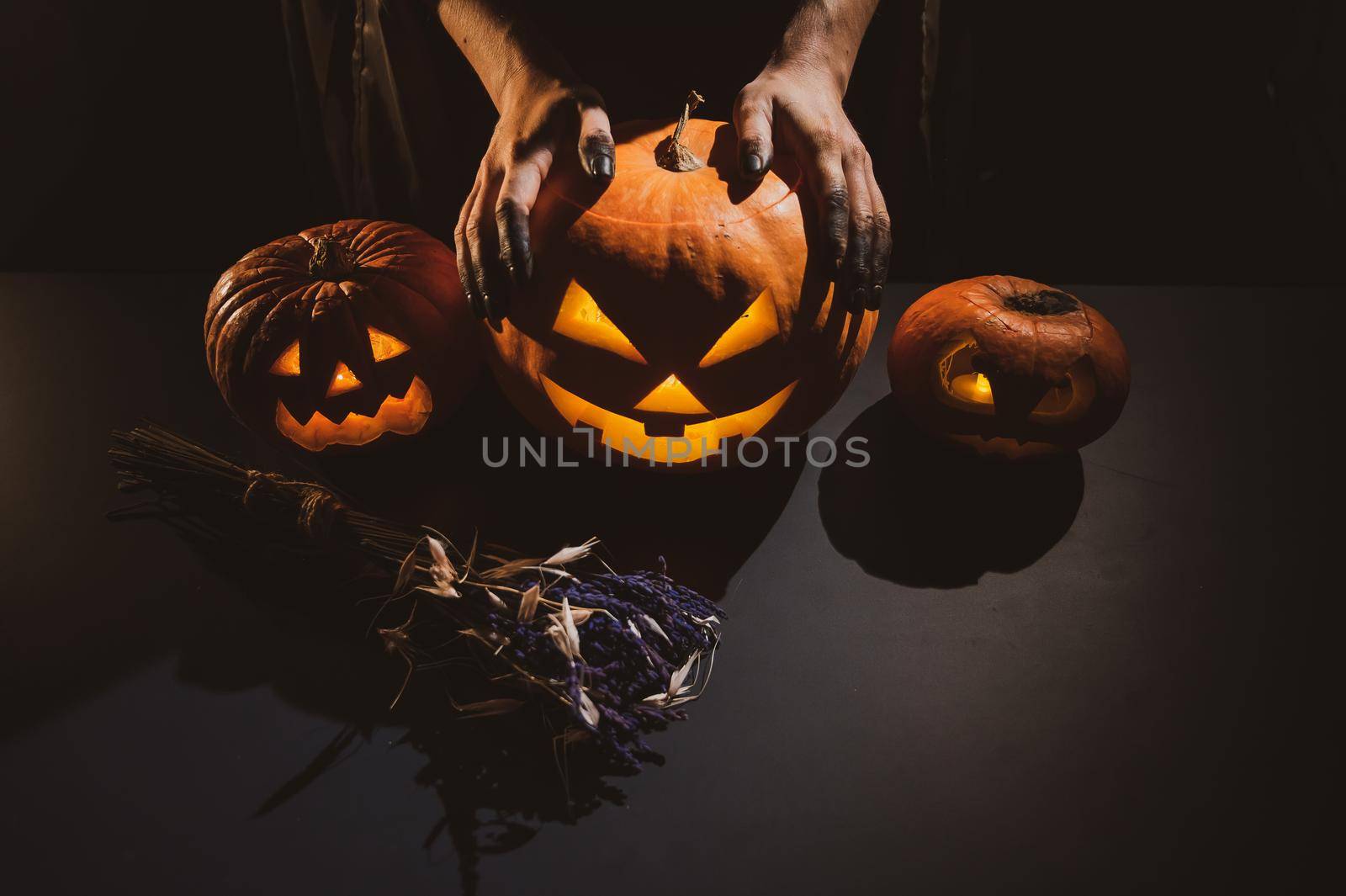 Close-up of female hands holding a halloween pumpkin in the dark by mrwed54