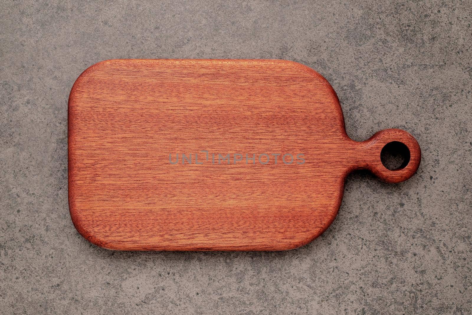 Empty vintage wooden cutting board set up on dark concrete background with copy space. by kerdkanno