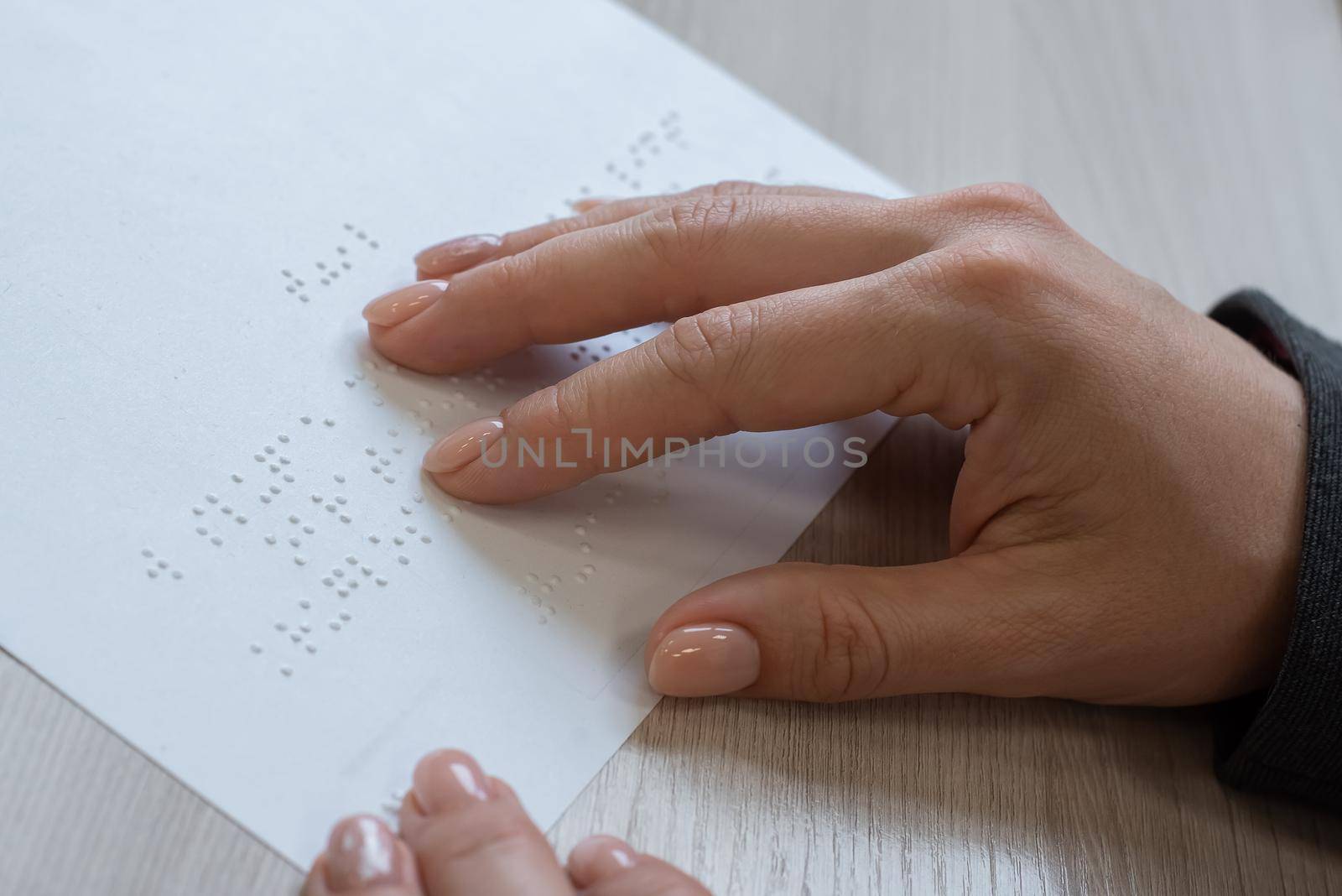 Close-up woman reads the text to the blind. Woman's hands on paper with braille code