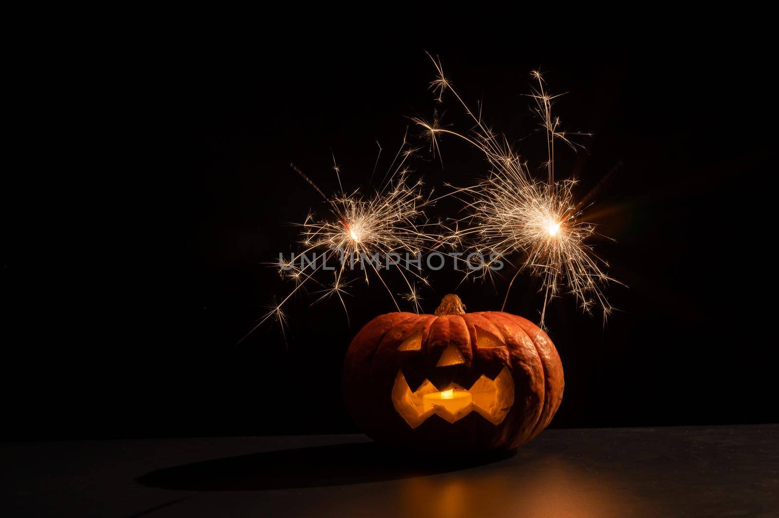 Halloween pumpkin with scary carved grimace and sparklers. by mrwed54