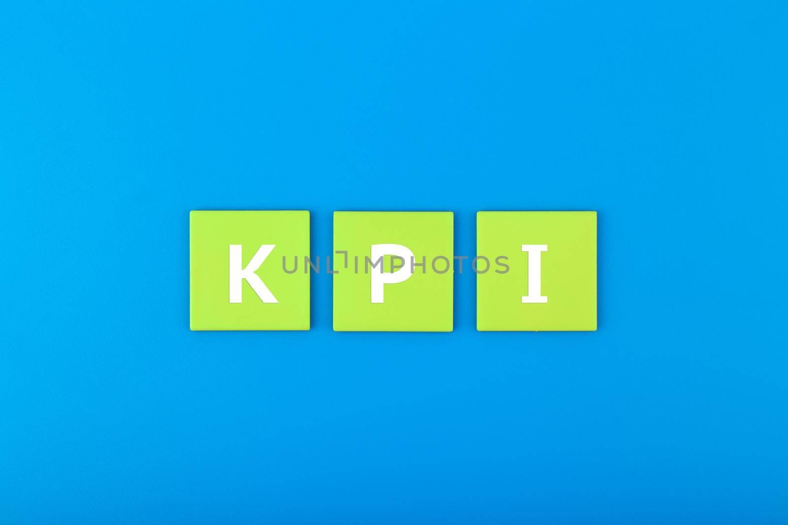 Minimal modern business KPI concept. KPI letters on light green tablets in a row against dark blue background with copy space. 