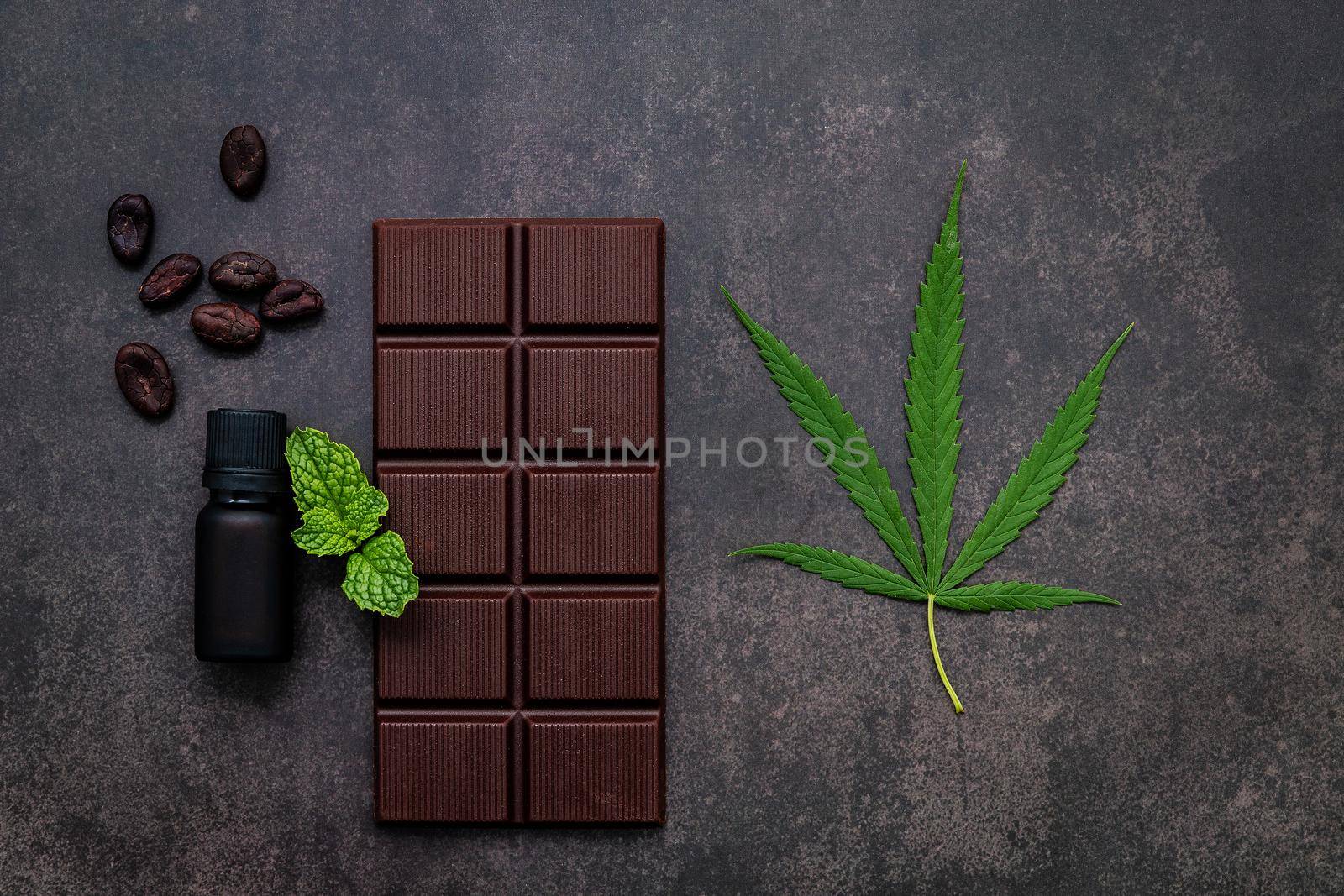 Food conceptual image of  cannabis leaf  with dark chocolate and fork on dark concrete background.