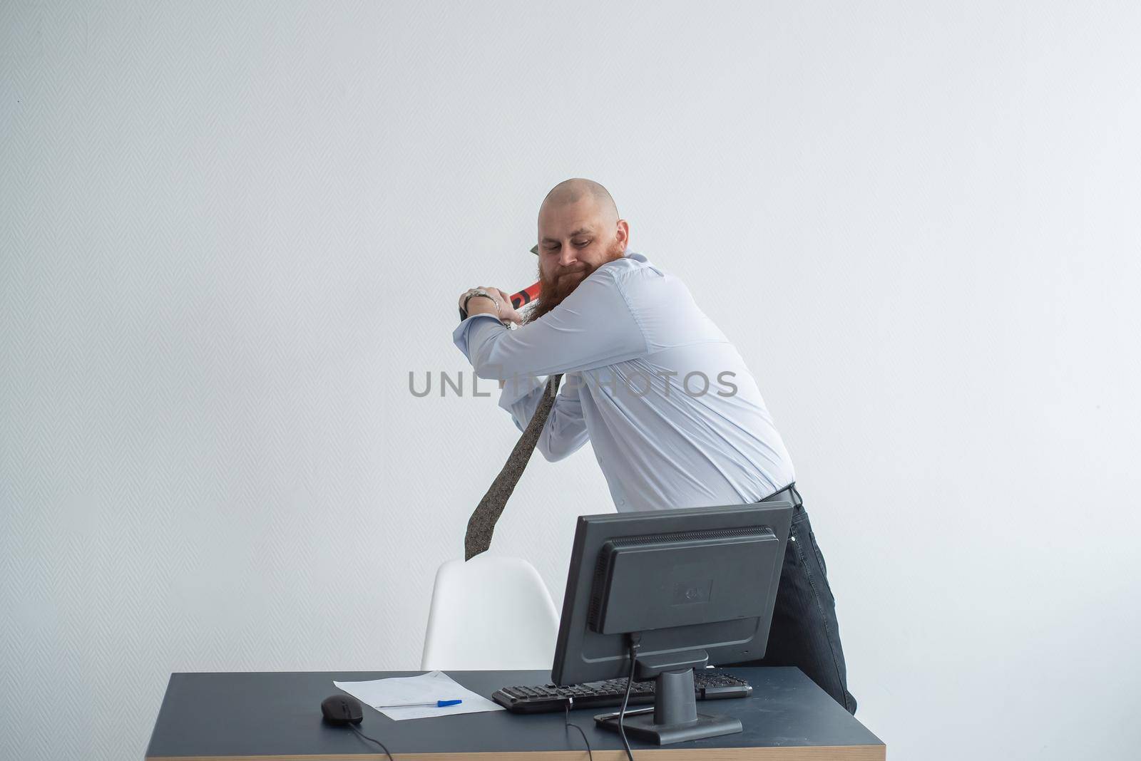 Stressed crazy businessman smashing his computer in office using ax problem concept. The man has problems at work and frustration