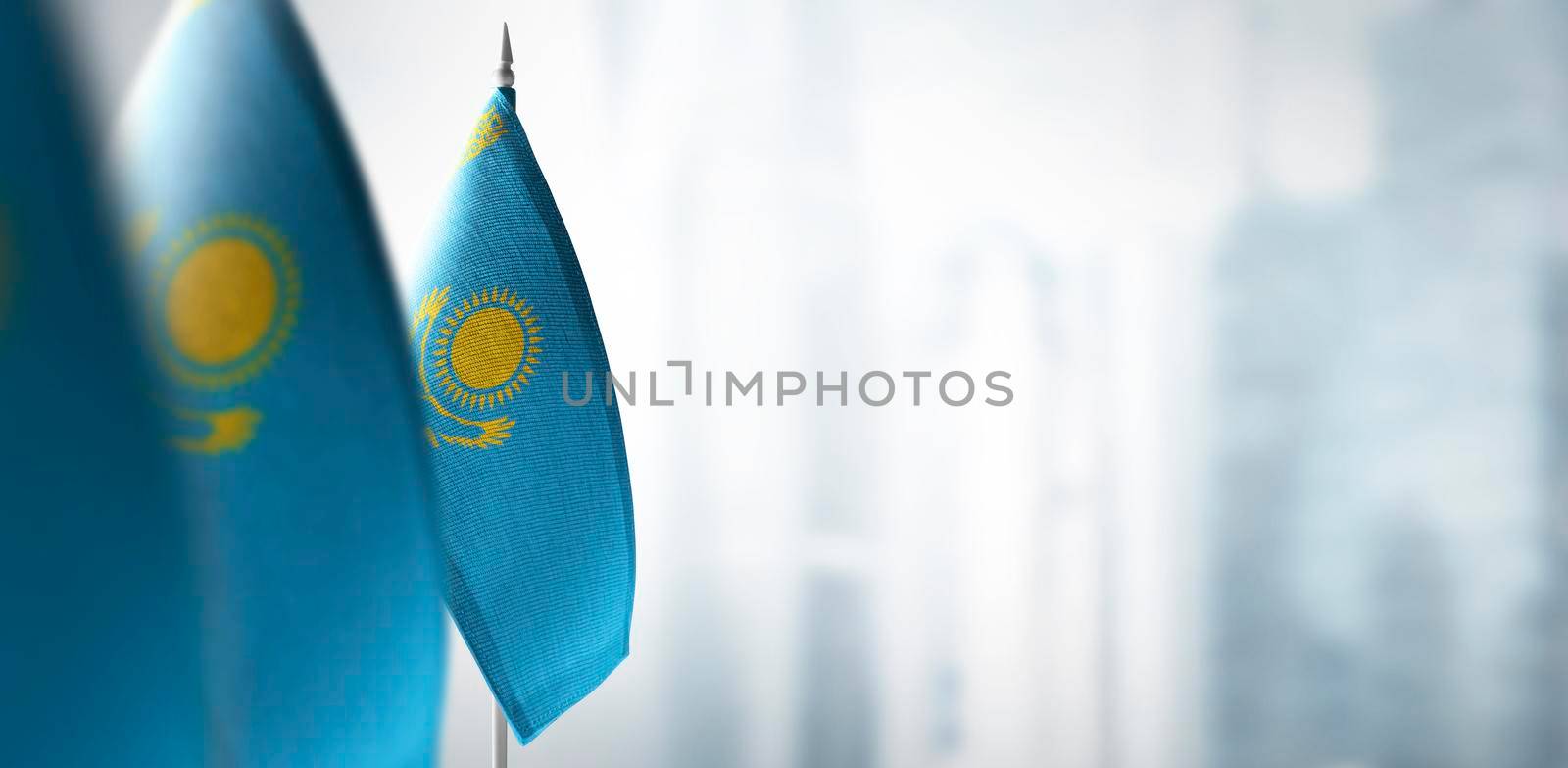 Small flags of Kazakhstan on a blurry background of the city.