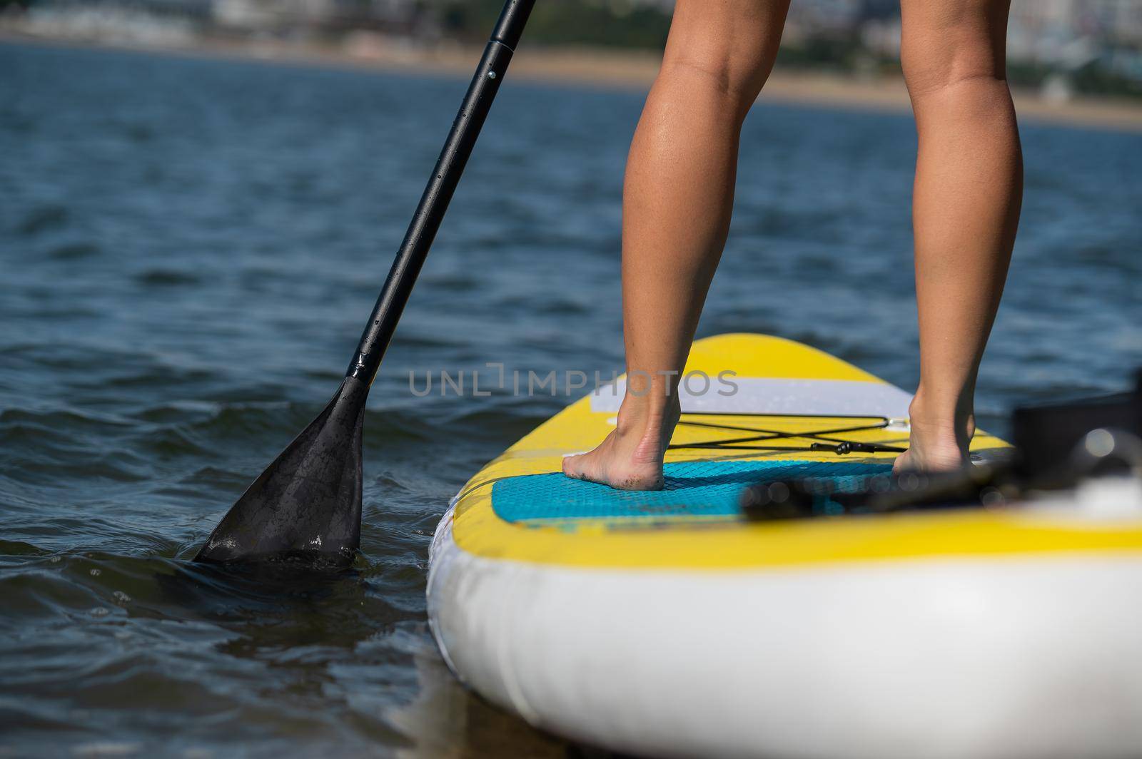 Caucasian woman swims on a SUP board. Close-up of female legs on the surf. by mrwed54