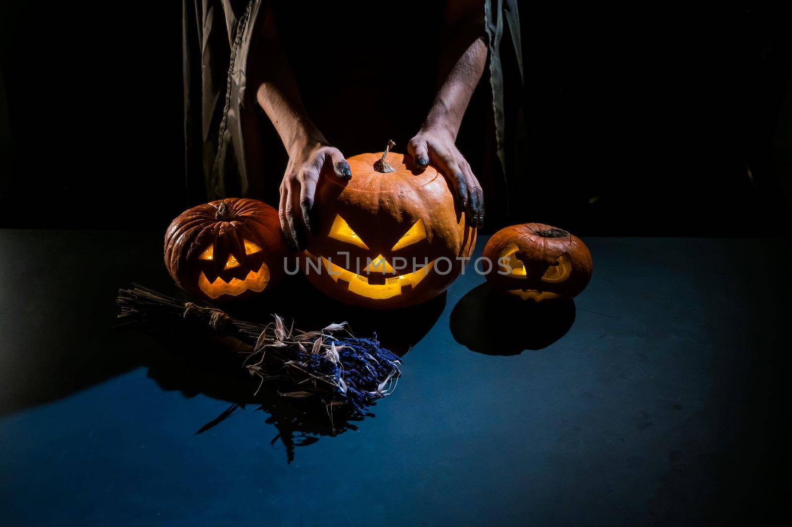 Close-up of female hands holding a halloween pumpkin in the dark.