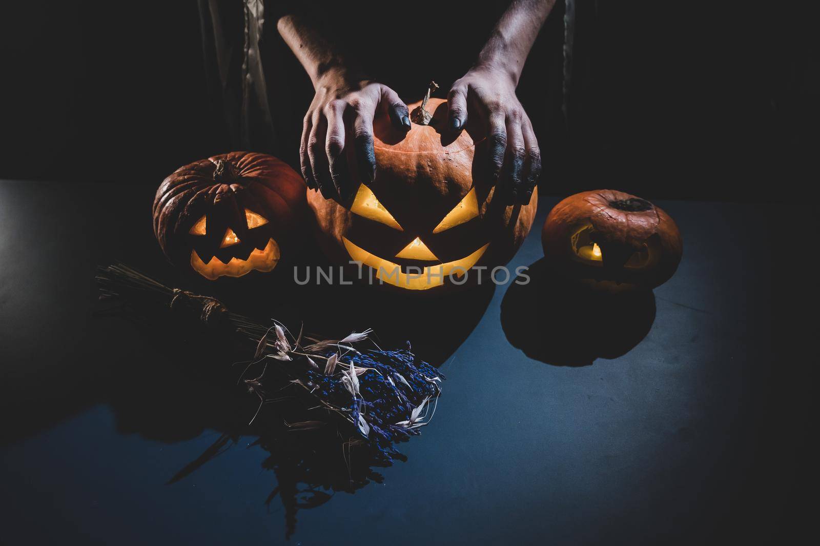 Close-up of female hands holding a halloween pumpkin in the dark.