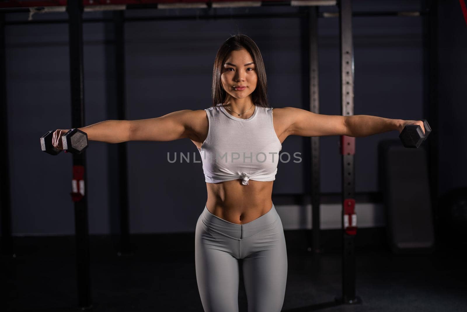 Asian woman doing exercises with dumbbells in the gym. by mrwed54