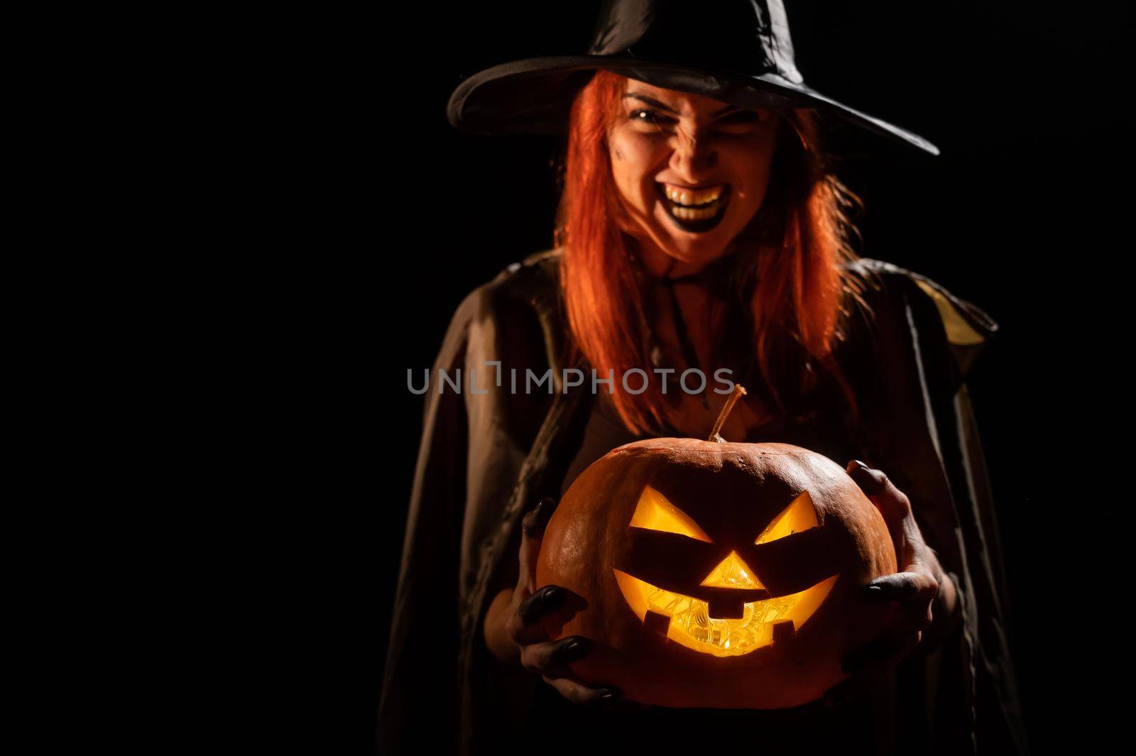 Wicked witch holding a jack-o-lantern for halloween.