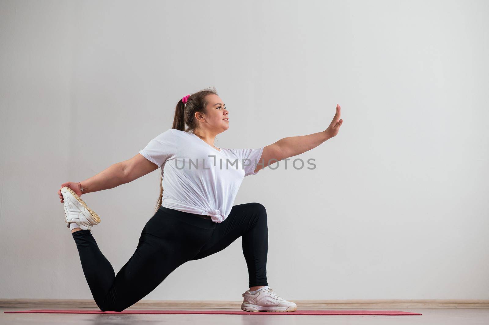 Young fat woman doing flexibility exercises on a white background by mrwed54