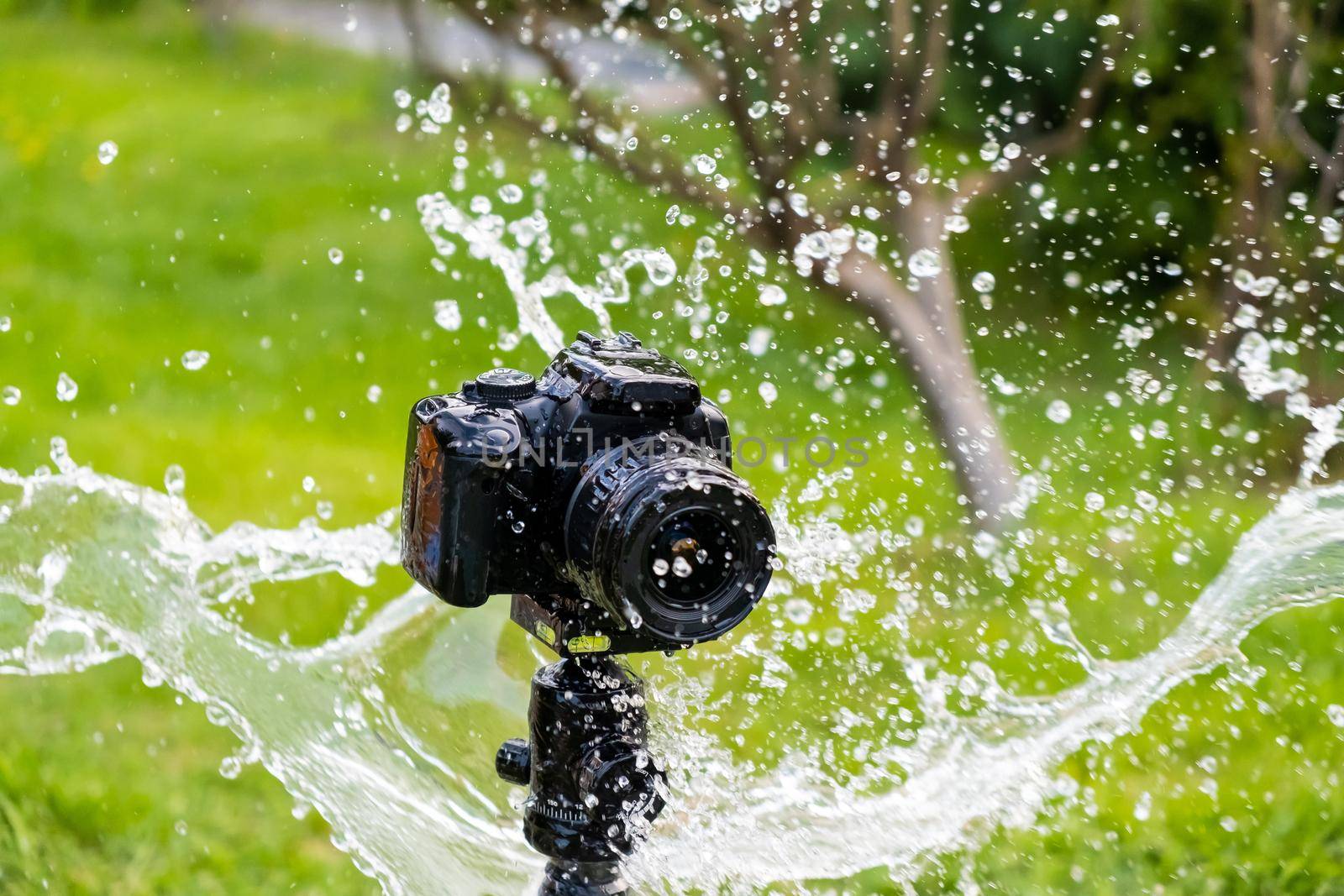 A digital camera on a tripod in the rain.