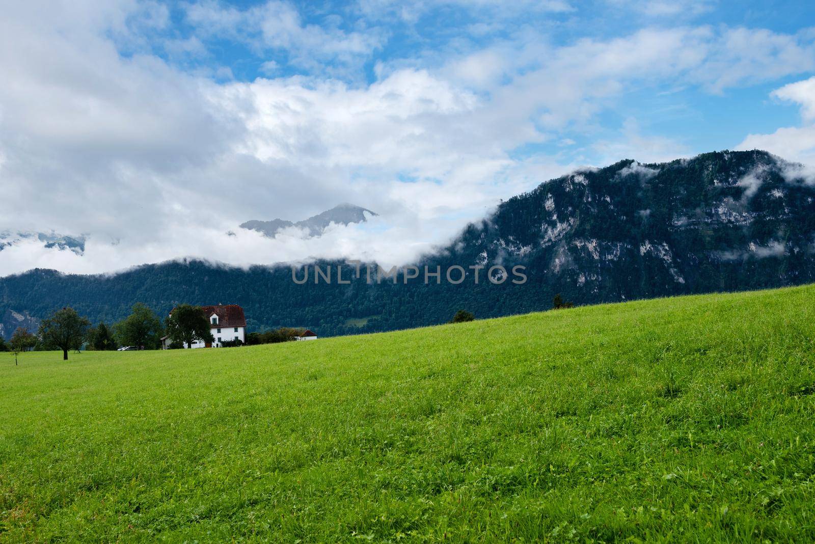 Beautiful green mountains landscape in Switzerland Alps. Small house by anytka
