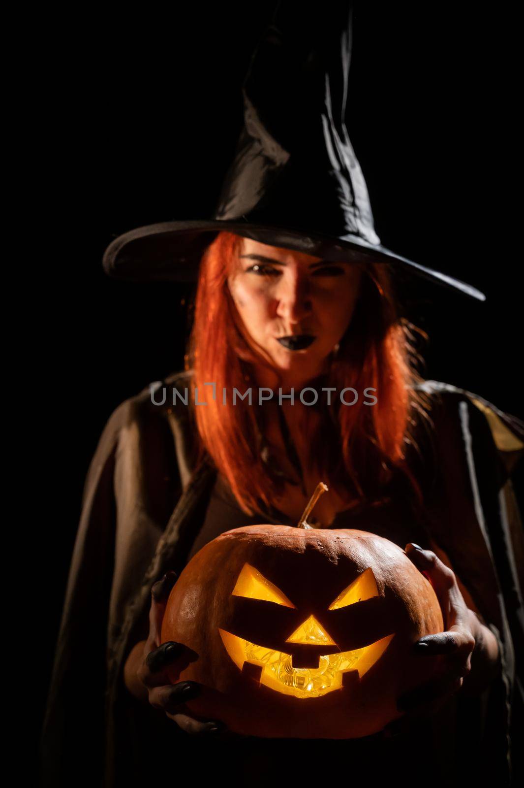 Wicked witch holding a jack-o-lantern for halloween.