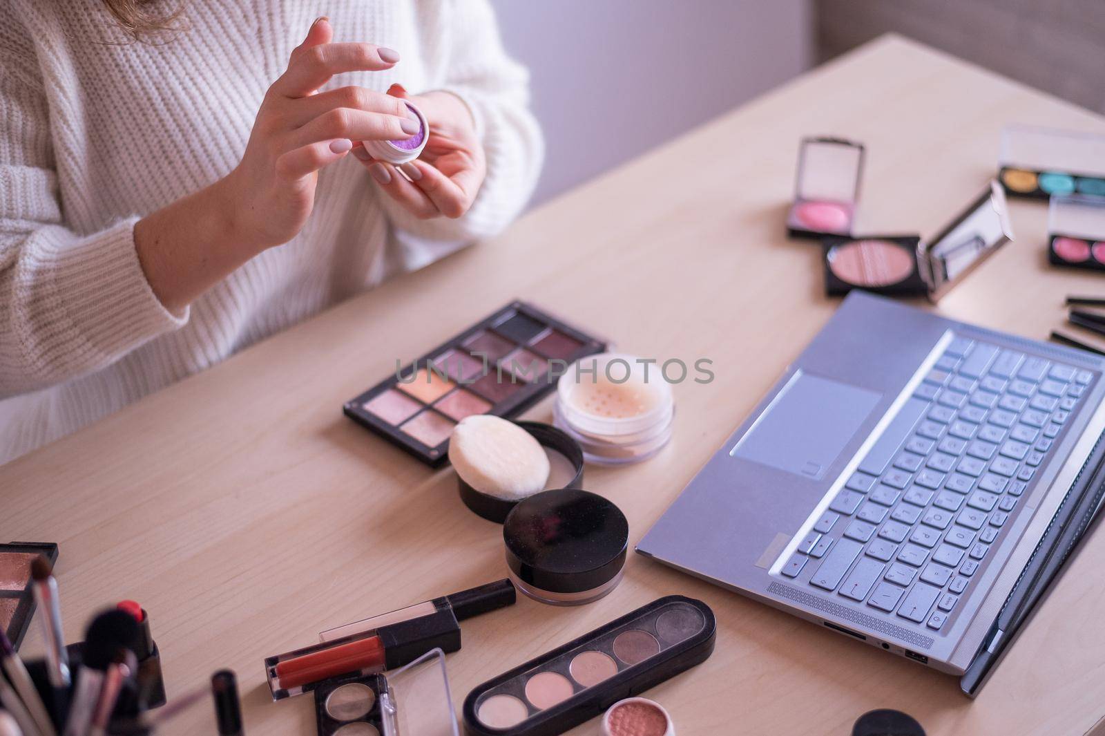 A faceless woman watches online training from a professional makeup artist on a laptop. Distance learning.